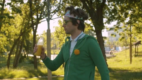 Funny freak in the park drinking juice Stock Footage 133965537