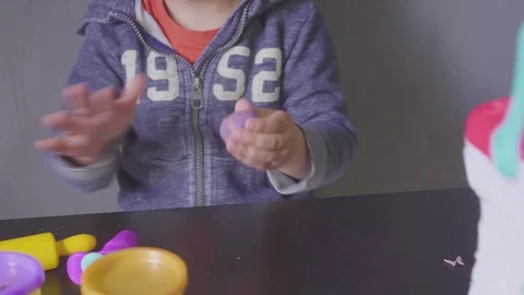 Funny Fun Three year old boy sculpting in plasticine on gray background 動画素材 129390454