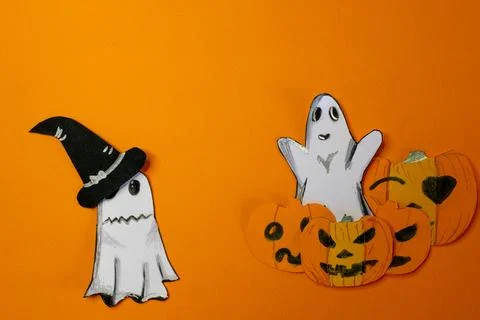 Funny ghost playing at scaring, coming out from behind pumpkins.Copy space Stock Photos