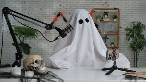 Funny ghost in a white sheet recording a podcast or blog Stock Footage 317250197