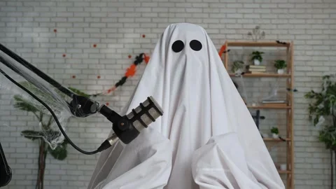 Funny ghost in a white sheet recording a podcast or blog Stock Footage 317250216