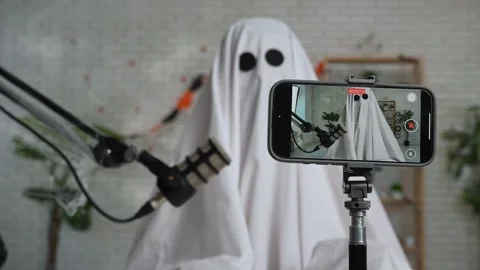 Funny ghost in a white sheet recording a podcast or blog Stock Footage 317250337