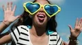 Funny girl in big glasses in shape of hearts looks at the camera and makes faces HD Footage