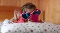 Funny girl in big glasses in the shape of hearts with smartphone lies on the bed HD Footage