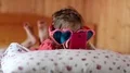 Funny girl in big glasses in the shape of hearts with smartphone lies on the bed HD Footage