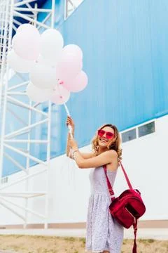Funny girl posing at camera while holding air balloons, outside. Stock Photos