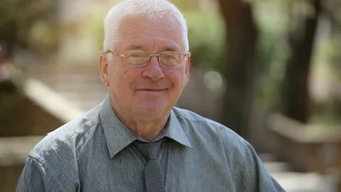 Funny grey-headed man in glasses stands and smiles in a street in summer Stock-Footage 89948768