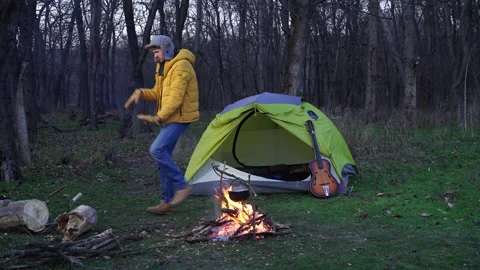 Funny guy dances near a tent and a campfire in the forest Stock-Footage 145320522
