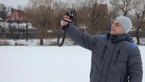 Funny guy doing selfie on camera on a pond in winter. Stock Footage 70759540