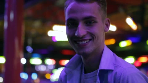 Funny guy laughs sitting near attractions in amusement park Stock Footage 139865546