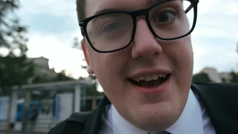Funny guy nerd in suit and glasses tells something to the camera very Video stock 136385543