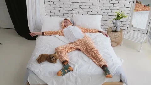 Funny guy in pajamas sleeps in bed lounging all over the bed Stock Footage 169814913