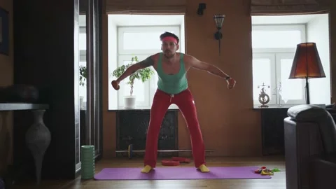 A funny guy trains with dumbbells alone at home Stock Footage 149075912