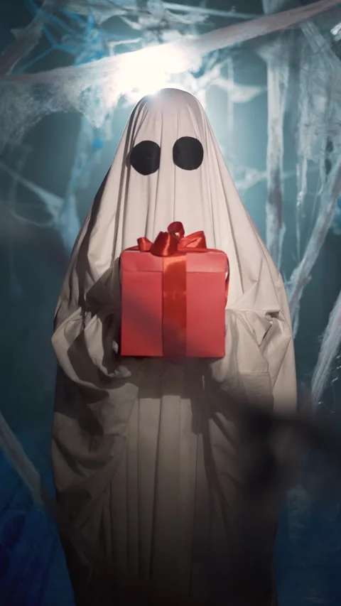 Funny halloween ghost with gift box and happy expression in dark corridor with Stock Footage 313948483