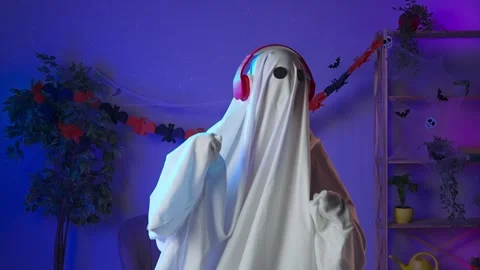 Funny halloween ghost in white sheet with black eyes in dark room dancing and 스톡 동영상 285741766
