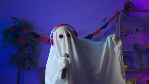 Funny halloween ghost in white sheet with black eyes in dark room dancing to Stock Footage 285741771