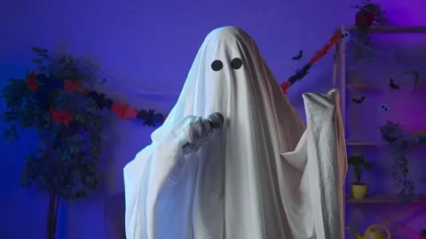 Funny halloween ghost in white sheet with black eyes in dark room dancing to Stock Footage 285741970