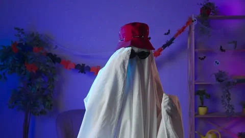 Funny halloween ghost in white sheet with black eyes in dark room wearing Stock Footage 285743212