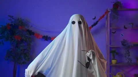 Funny halloween ghost in white sheet with black eyes in dark room wearing Stock Footage 285743402