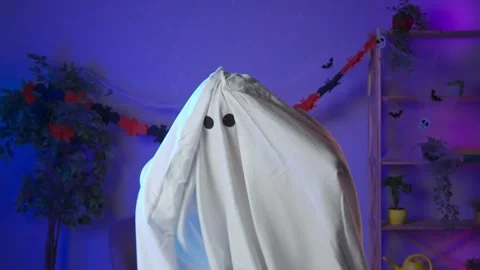 Funny halloween ghost in white sheet with black eyes in dark room worried Stock Footage 285743753