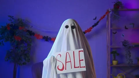 Funny halloween ghost in white sheet with black eyes in dark room holding Stock Footage 285744559