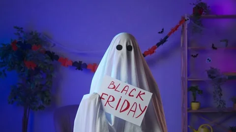 Funny halloween ghost in white sheet with black eyes in dark room holding Stock Footage 285744756