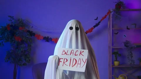 Funny halloween ghost in white sheet with black eyes in dark room holding Stock Footage 285744836