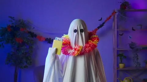 Funny halloween ghost in white sheet with black eyes in dark room holding Stock Footage 285744919