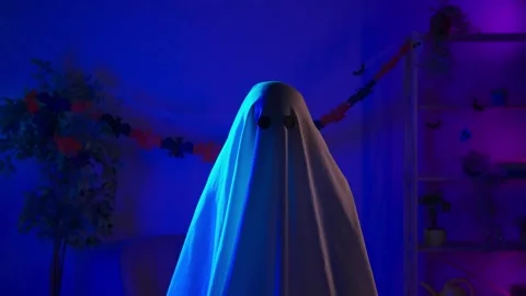 Funny halloween ghost in white sheet with black eyes in dark room and lighted up Stock Footage 285745411