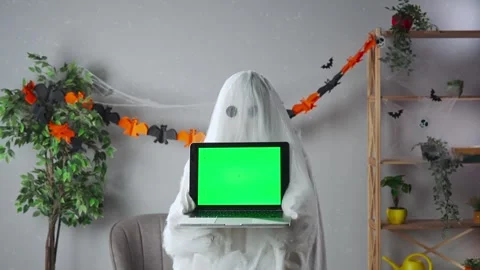 Funny halloween ghost in white sheet with black eyes in bright room holding Stock Footage 285746364