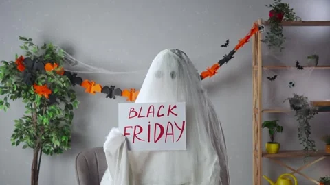 Funny halloween ghost in white sheet with black eyes in bright room holding Stock Footage 285746688