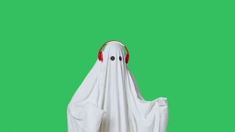 Funny halloween ghost in white sheet wearing headphone dancing listening music Stock Footage 285747535