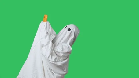 Funny halloween ghost in white sheet talking on smartphone by video call Stock Footage 285748379