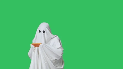 Funny halloween ghost in white sheet playing online video game on smartphone Stock Footage 285748775
