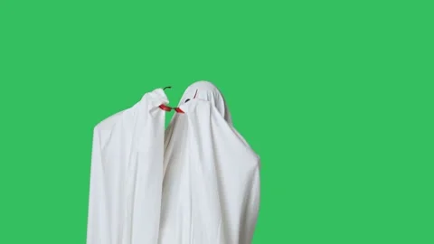 Funny halloween ghost in white sheet takes off red glasses looks around Stock Footage 285750203