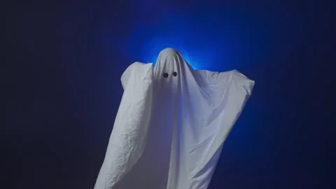 Funny Halloween ghost in white sheet makes scary gestures on background with Stock Footage 285751483