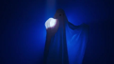 Funny halloween ghost in white sheet silhouette moving under ray of white light Stock Footage 285751804