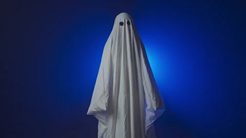 Funny Halloween ghost in white sheet makes scary gestures on background with Stock Footage 285753274