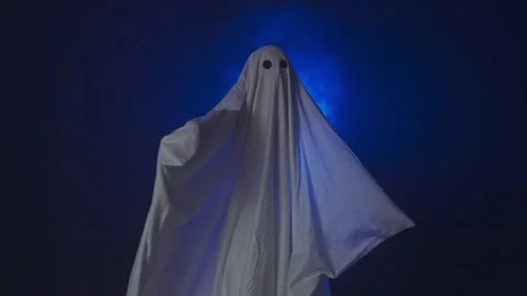 Funny Halloween ghost in white sheet makes scary gestures on background with Stock Footage 285753372