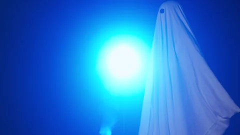 Funny halloween ghost in white sheet silhouette walking past bright blue Stock Footage 285753729
