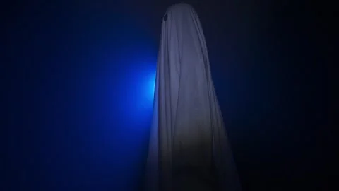 Funny halloween ghost in white sheet silhouette walking past bright blue Stock Footage 285754140