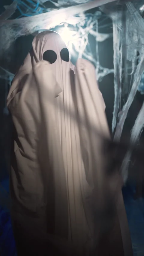 Funny halloween ghost in white sheet actively dancing in dark corridor with Stock Footage 313948524
