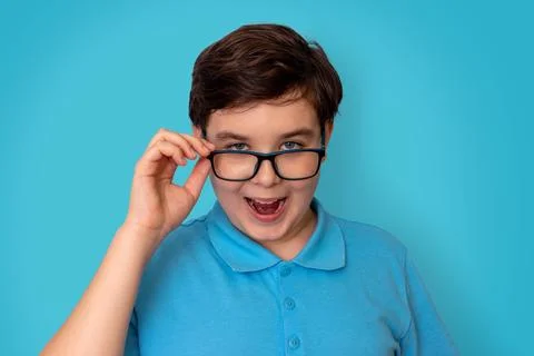 A funny handsome boy, dark-haired, wearing glasses and a blue T-shirt, Stock Photos