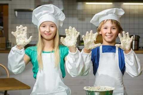 Funny happy chef boy width girl cooking at restaurant kitchen and knead the Stock Photos