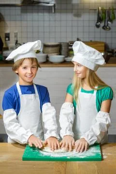Funny happy chef boy width girl cooking at restaurant kitchen and rolls the Stock Photos