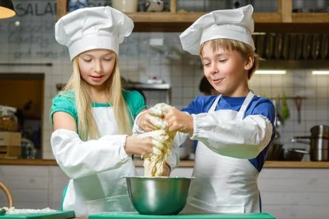 Funny happy chef boy width girl cooking at restaurant kitchen and knead the Stock Photos