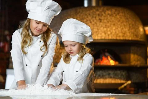 Funny happy chef boy width girl cooking at restaurant kitchen and knead the Foto stock