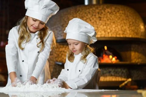 Funny happy chef boy width girl cooking at restaurant kitchen and knead the Stock Photos