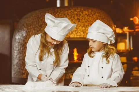 Funny happy chef boy width girl cooking at restaurant kitchen and knead the Stock Photos
