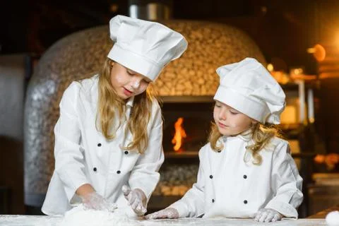 Funny happy chef boy width girl cooking at restaurant kitchen and knead the Stock Photos